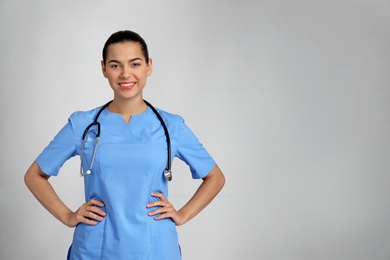 Portrait of young medical assistant with stethoscope on color background. Space for text