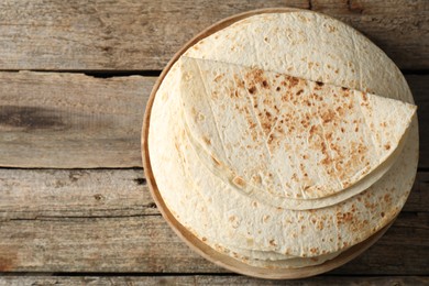 Photo of Stack of tasty homemade tortillas on wooden table, top view. Space for text