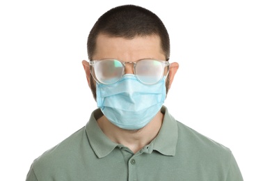 Man with foggy glasses caused by wearing disposable mask on white background. Protective measure during coronavirus pandemic