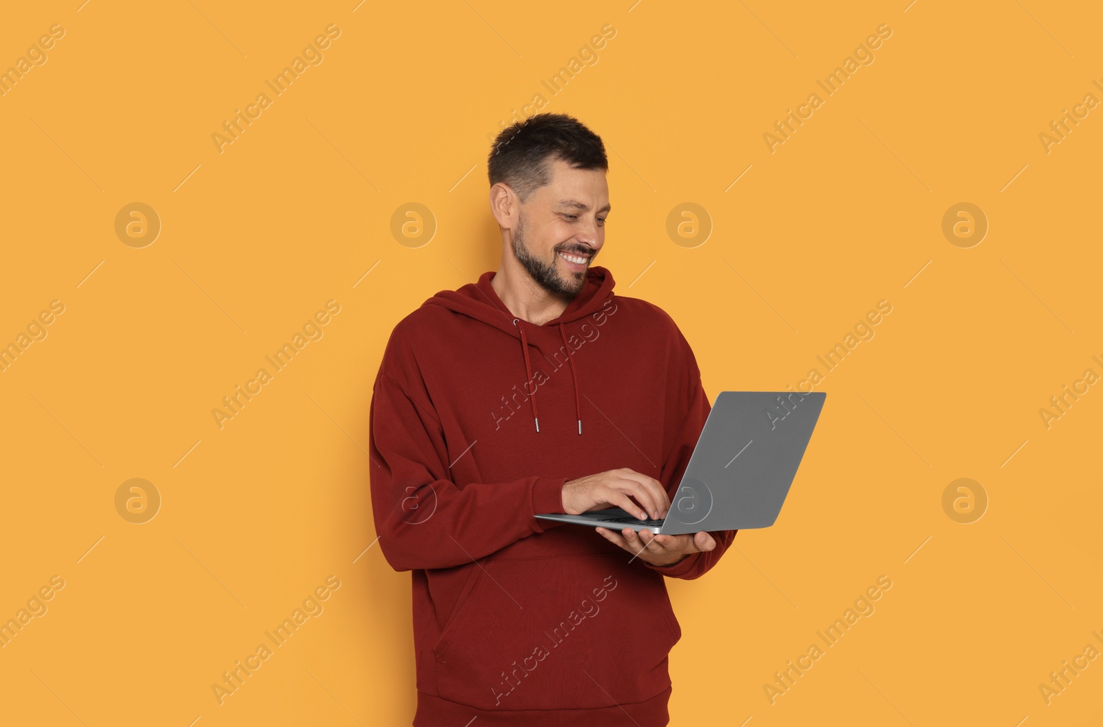 Photo of Happy man with laptop on orange background