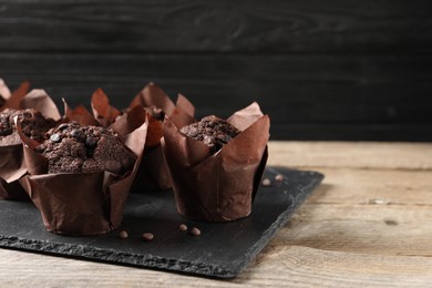 Photo of Delicious chocolate muffins on wooden table. Space for text