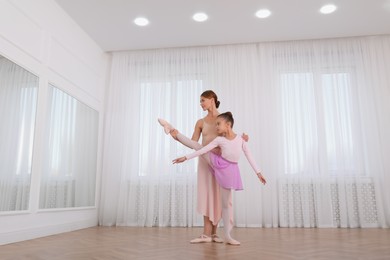 Little ballerina and her teacher practicing dance moves in studio