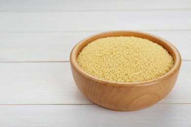 Bowl of raw couscous on white wooden table. Space for text