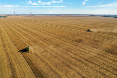 Beautiful aerial view of modern combine harvester working in field on sunny day. Agriculture industry