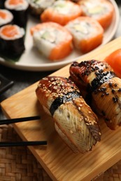 Photo of Different tasty sushi rolls and chopsticks on table