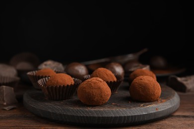 Photo of Delicious chocolate truffles powdered with cocoa on wooden table, space for text