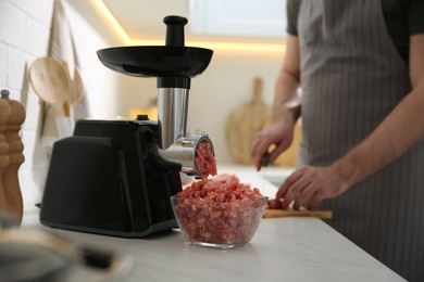 Photo of Closeup view of man cutting ingredients in kitchen, focus on meat grinder
