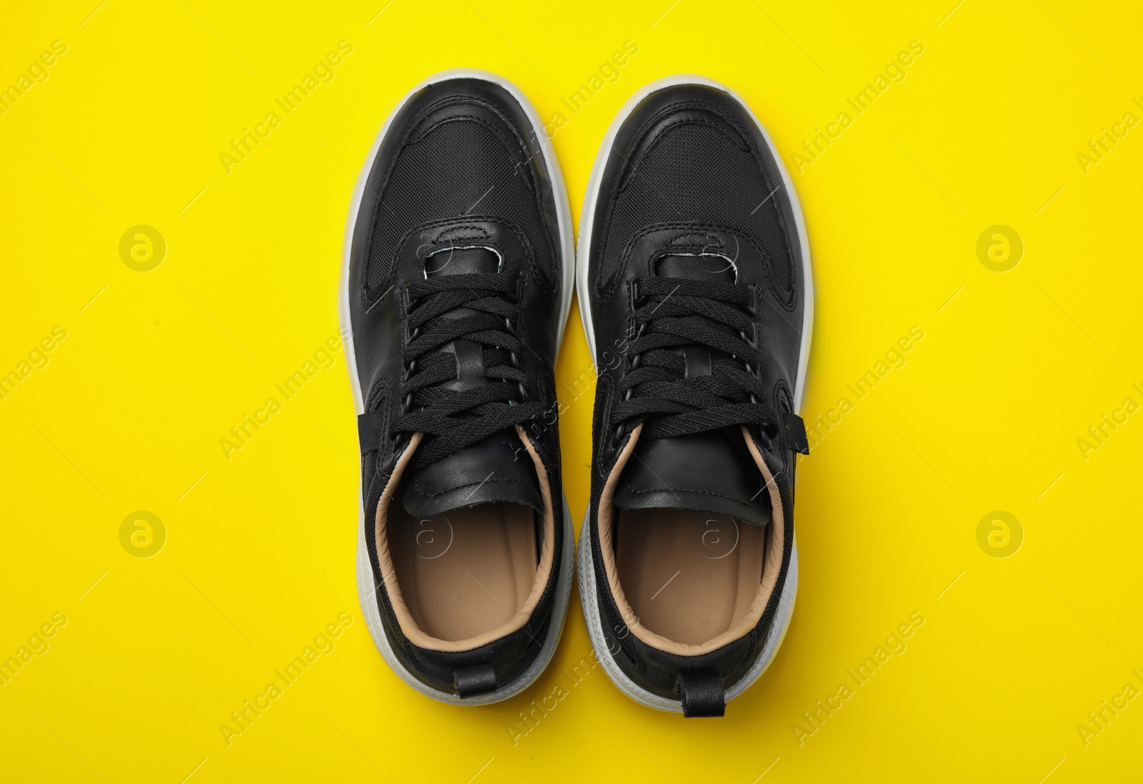 Photo of Pair of stylish shoes on yellow background, top view