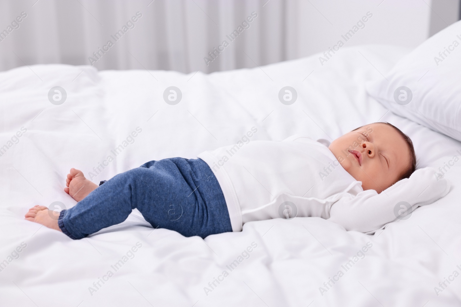 Photo of Cute newborn baby sleeping on white bed at home