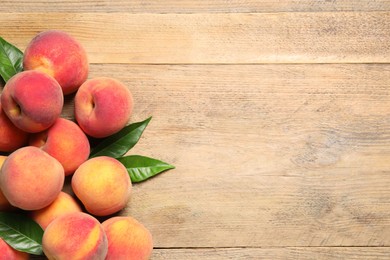 Photo of Fresh peaches and leaves on wooden table, flat lay. Space for text