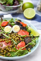 Photo of Plate of salad with mung beans on white marble table, closeup