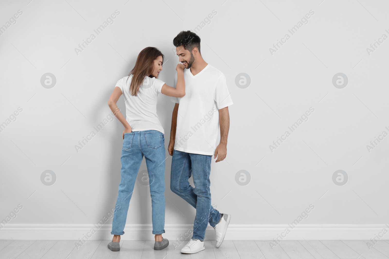 Photo of Young couple in stylish jeans near light wall