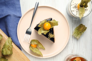 Delicious dessert decorated with physalis fruit on white wooden table, flat lay