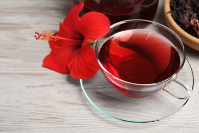 Photo of Delicious hibiscus tea and beautiful flower on light wooden table, closeup