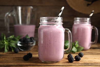 Photo of Tasty milk shake with blackberries on wooden table