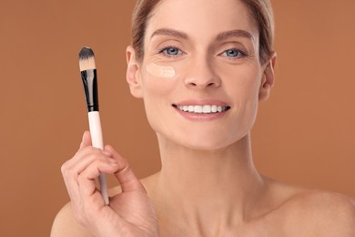Photo of Woman with swatch of foundation and makeup brush against brown background