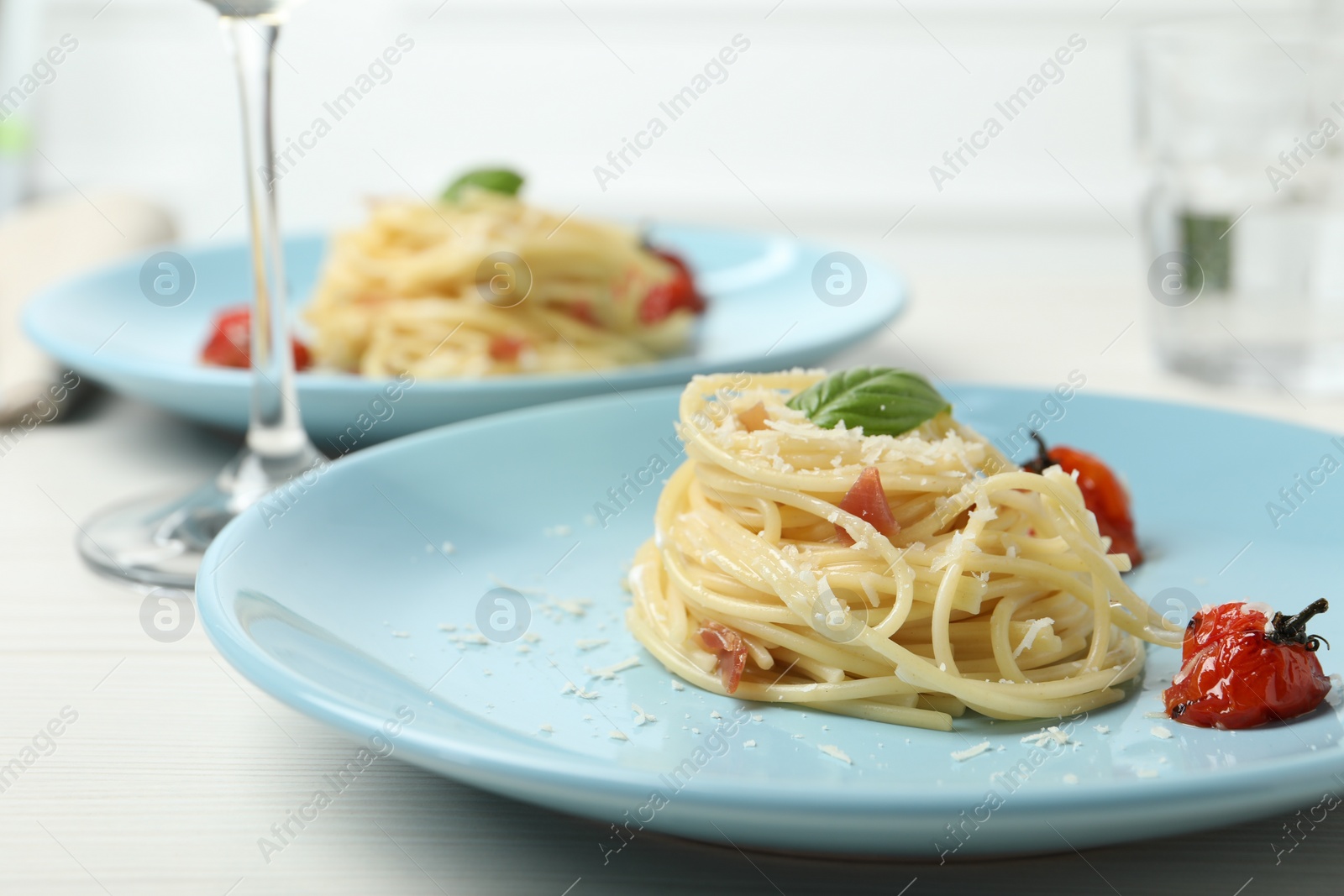 Photo of Tasty spaghetti with tomatoes and cheese served on white wooden table, closeup. Exquisite presentation of pasta dish