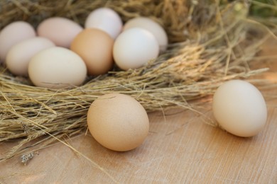 Nest with fresh raw eggs on wooden table, closeup