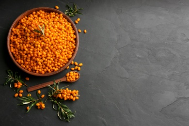 Fresh ripe sea buckthorn on black table, flat lay. Space for text
