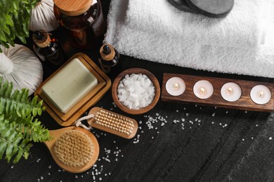 Photo of Flat lay composition with different spa products and burning candles on black table