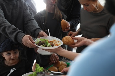 Photo of Poor people receiving food from volunteer indoors, closeup