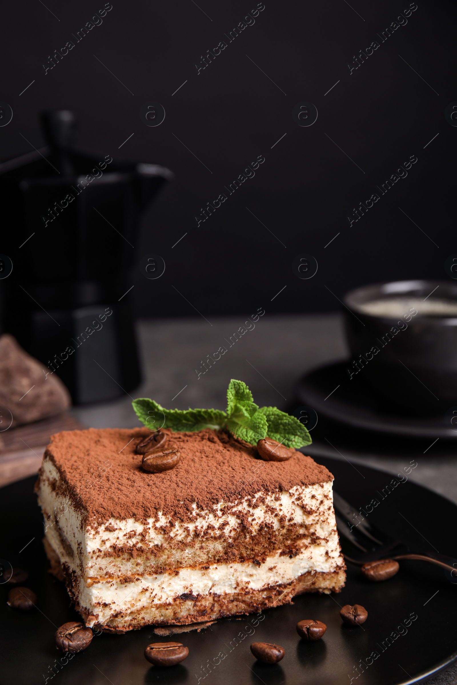 Photo of Composition with tiramisu cake on table against dark background