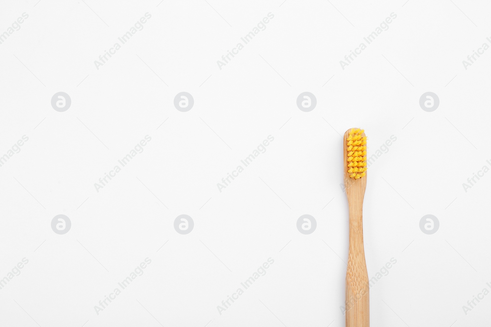Photo of Bamboo toothbrush with yellow bristle isolated on white, top view