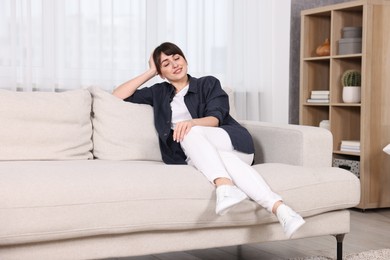 Photo of Beautiful young housewife resting on sofa at home