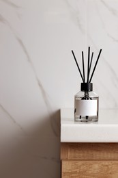 Photo of Aromatic reed air freshener on white table indoors, space for text