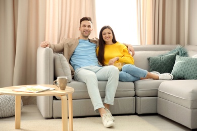 Happy young couple watching TV on sofa at home