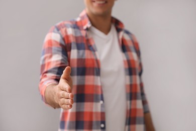 Photo of Man reaching out for handshake on grey background, closeup