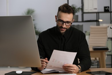 Photo of Man working with document at table in office