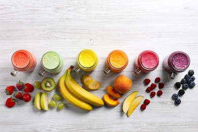 Photo of Many different tasty smoothies and ingredients on white wooden table, flat lay. Space for text