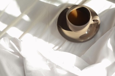 Photo of Cup of aromatic coffee on bed in morning, above view. Space for text