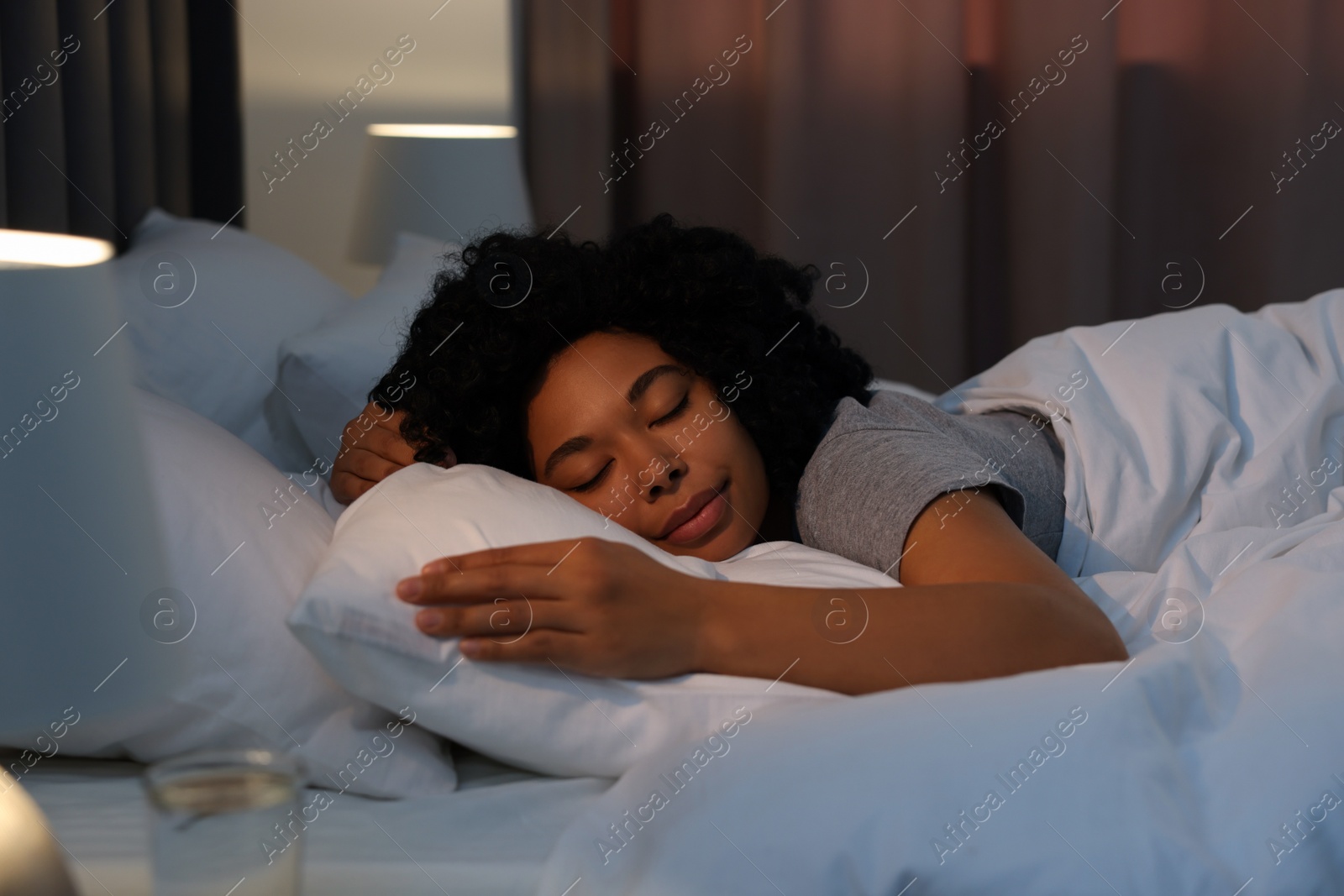 Photo of Young woman sleeping in soft bed at night