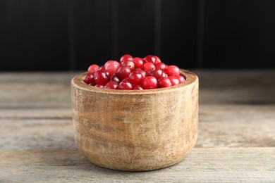 Photo of Ripe cranberries in bowl on wooden table