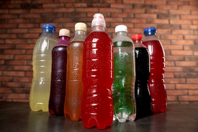 Bottles of soft drinks with water drops on table near brick wall