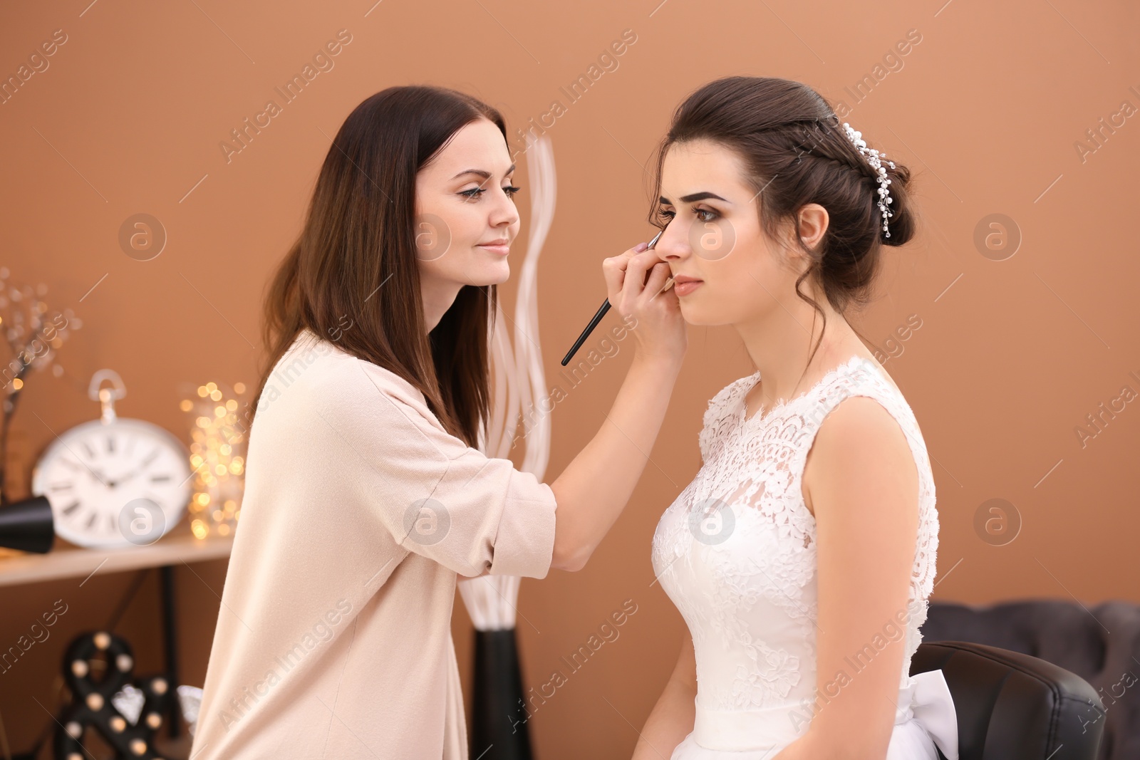 Photo of Professional makeup artist working with young bride in salon