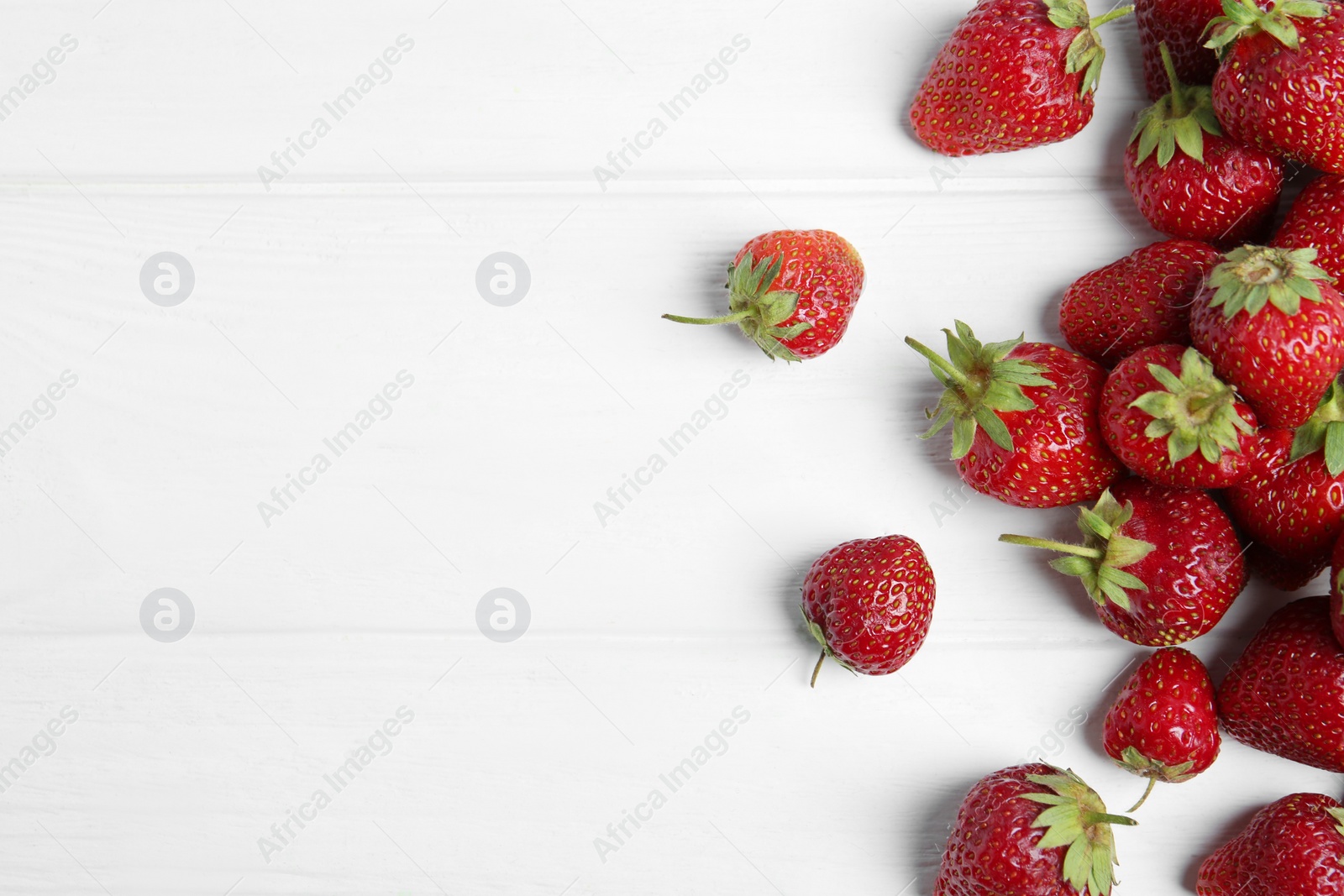 Photo of Delicious ripe strawberries on white wooden table, flat lay. Space for text