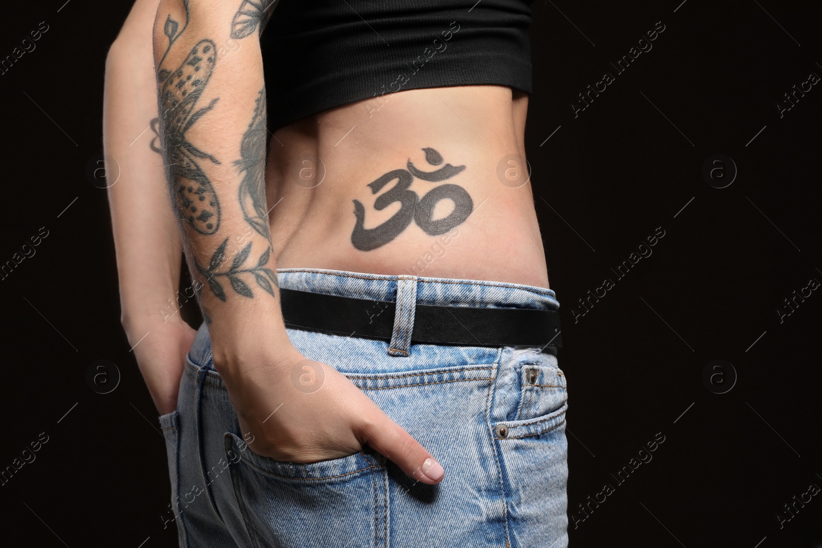 Photo of Woman with tattoos on body against black background, closeup