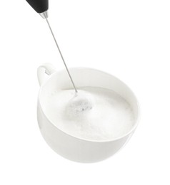 Photo of Whisking milk in cup with mini mixer (frother wand) isolated on white, closeup