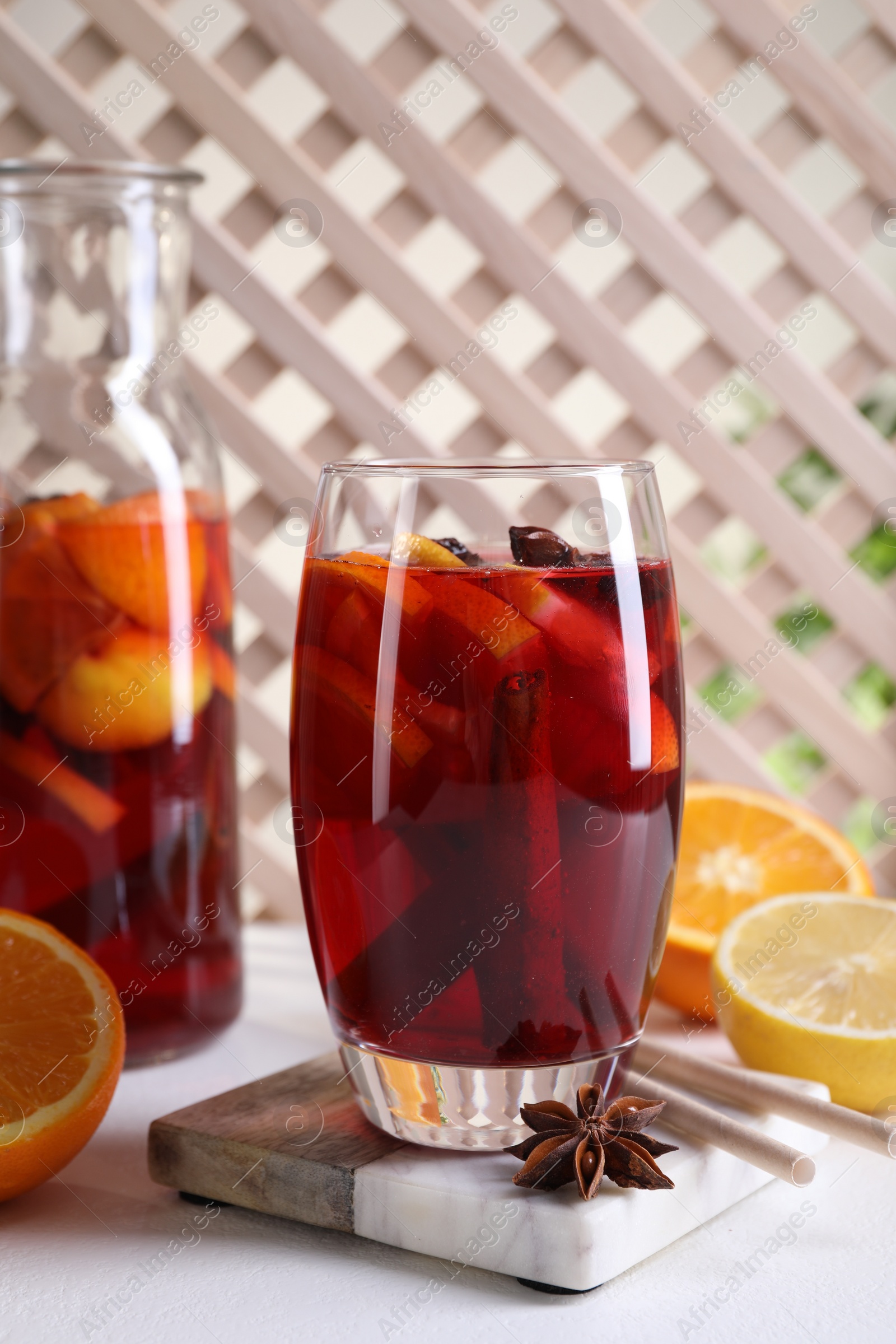 Photo of Aromatic punch drink and ingredients on white table