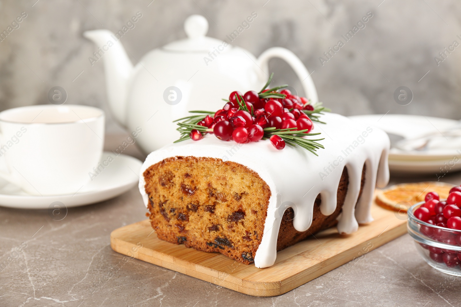 Photo of Traditional classic Christmas cake decorated with cranberries, pomegranate seeds and rosemary served on table