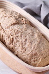 Photo of Fresh sourdough in proofing basket on table, above view