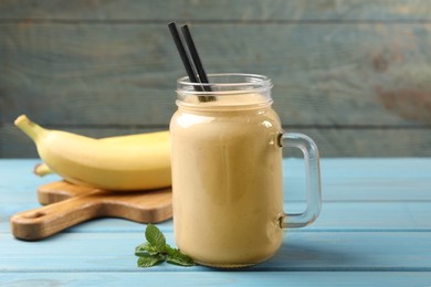 Photo of Mason jar with banana smoothie on light blue wooden table