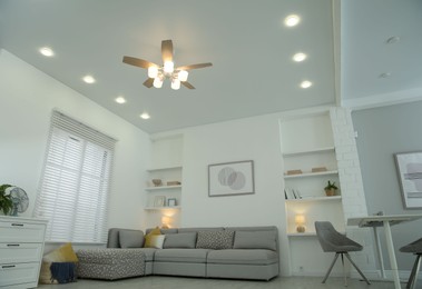 Photo of Comfortable furniture, ceiling fan and accessories in stylish living room