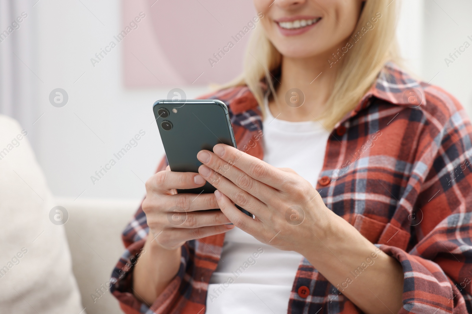 Photo of Happy woman sending message via smartphone at home, closeup