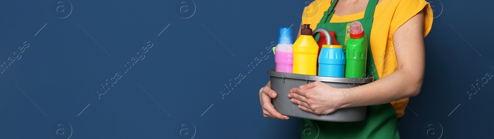 Image of Closeup view of woman with detergents on blue background, banner design with space for text. Cleaning service