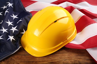 Yellow protective hard hat and American flag on wooden table