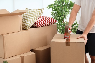 Photo of Man packing carton box indoors, closeup. Moving day